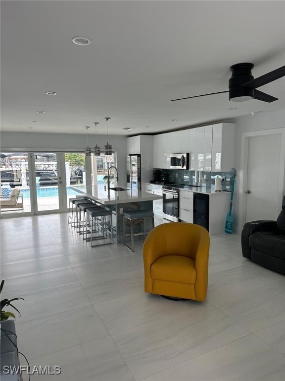 living room featuring wine cooler, ceiling fan, and sink