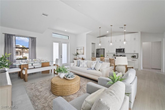 living room featuring high vaulted ceiling and light hardwood / wood-style flooring