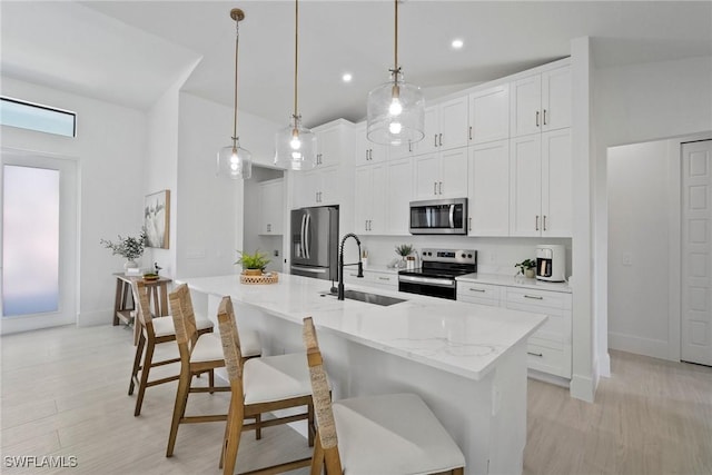 kitchen with appliances with stainless steel finishes, sink, pendant lighting, a kitchen breakfast bar, and white cabinets