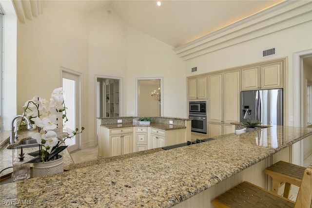 kitchen with stainless steel appliances, cream cabinetry, and light stone countertops