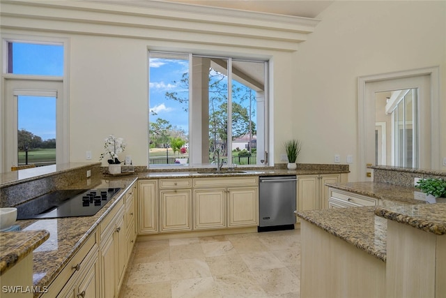 kitchen with cream cabinetry, light stone counters, a sink, and black electric cooktop