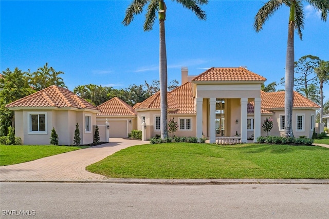 mediterranean / spanish home with a front yard, a chimney, and stucco siding