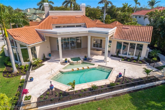 rear view of house with a tiled roof, a patio area, fence private yard, and stucco siding