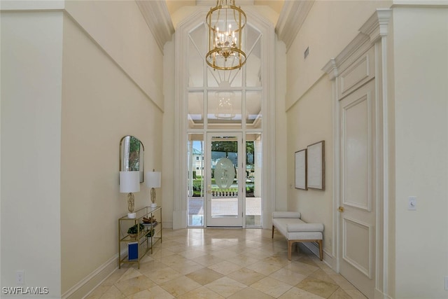 entrance foyer with baseboards, ornamental molding, a towering ceiling, and an inviting chandelier