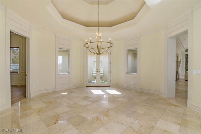 spare room with crown molding, a tray ceiling, baseboards, and a notable chandelier