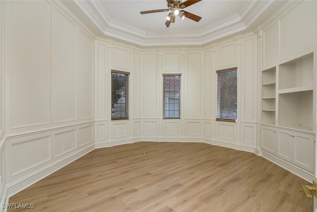 empty room with light wood-type flooring, ornamental molding, a decorative wall, and built in features