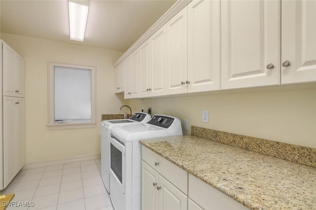 laundry area featuring light tile patterned floors, cabinet space, baseboards, and separate washer and dryer