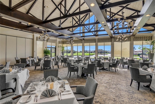 dining room featuring a healthy amount of sunlight, beamed ceiling, a high ceiling, and an inviting chandelier