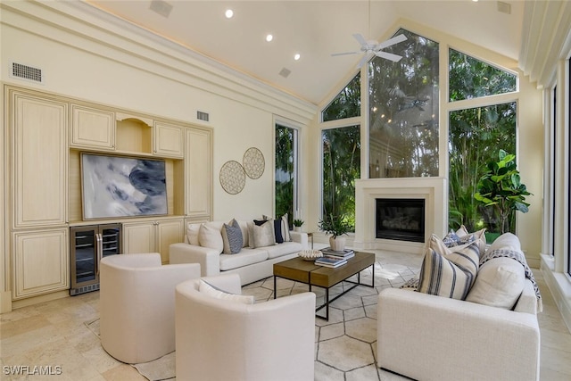 living room featuring beverage cooler, high vaulted ceiling, a glass covered fireplace, and visible vents