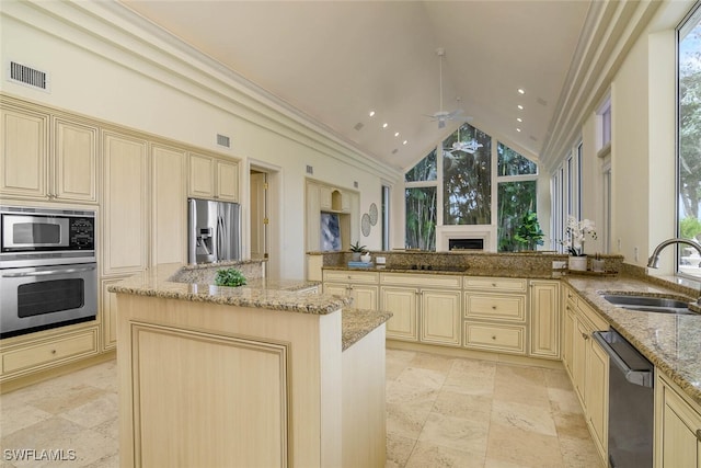 kitchen featuring light stone countertops, black appliances, cream cabinets, and a sink