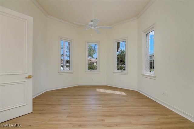 spare room with ceiling fan, ornamental molding, light wood-style flooring, and baseboards