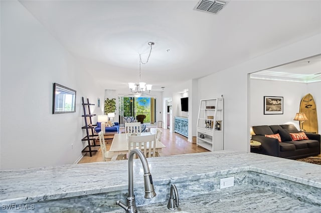 kitchen featuring a notable chandelier, visible vents, hanging light fixtures, open floor plan, and wood finished floors