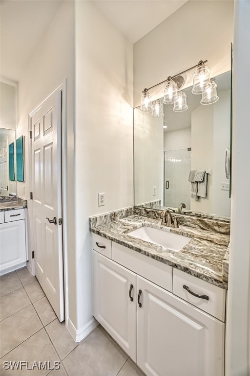 full bath featuring tile patterned flooring, baseboards, a shower stall, and vanity