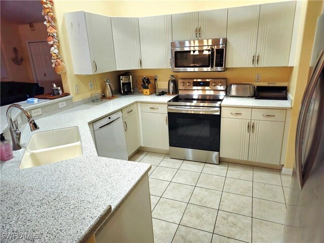 142 SE 30th Ter, Cape Coral, FL 33904 - kitchen featuring appliances with stainless steel finishes, a sink, light tile patterned flooring, a peninsula, and light stone countertops