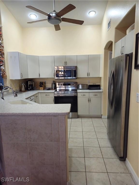 142 SE 30th Ter, Cape Coral, FL 33904 - kitchen featuring stainless steel appliances, a sink, a peninsula, a ceiling fan, and light tile patterned floors