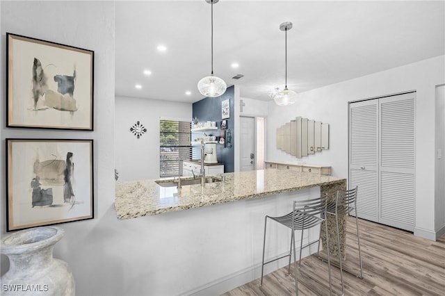 kitchen featuring light stone counters, recessed lighting, and wood finished floors