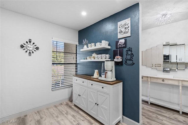 interior space featuring light wood finished floors, stainless steel microwave, and baseboards