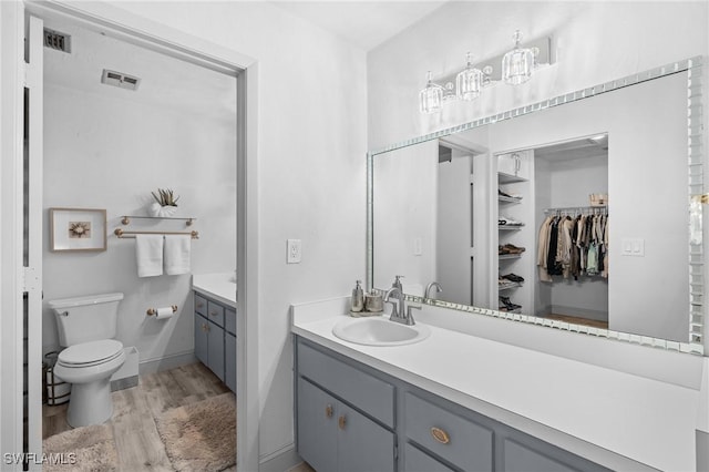 full bathroom with toilet, wood finished floors, vanity, visible vents, and baseboards