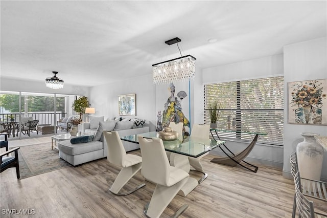 dining area with light wood finished floors and a notable chandelier