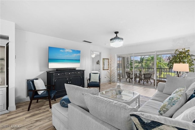 living area featuring light wood-type flooring, visible vents, and baseboards