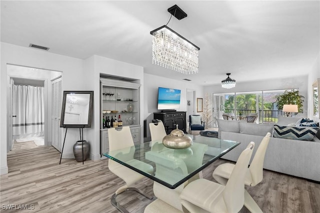 dining space with an inviting chandelier, visible vents, and light wood-style floors