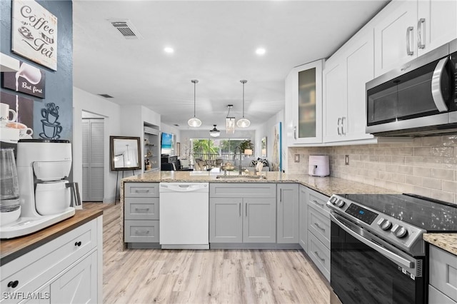 kitchen with visible vents, decorative backsplash, glass insert cabinets, appliances with stainless steel finishes, and a sink