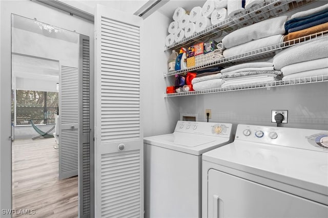 clothes washing area featuring laundry area, washer and clothes dryer, and light wood finished floors