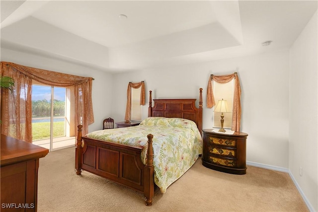 carpeted bedroom featuring a raised ceiling and access to exterior