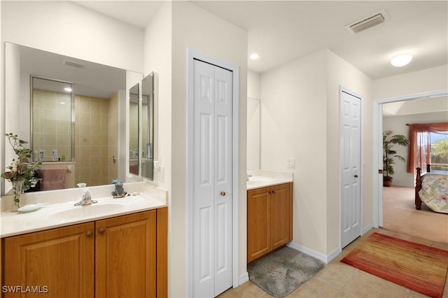 bathroom with a tile shower, tile patterned flooring, and vanity