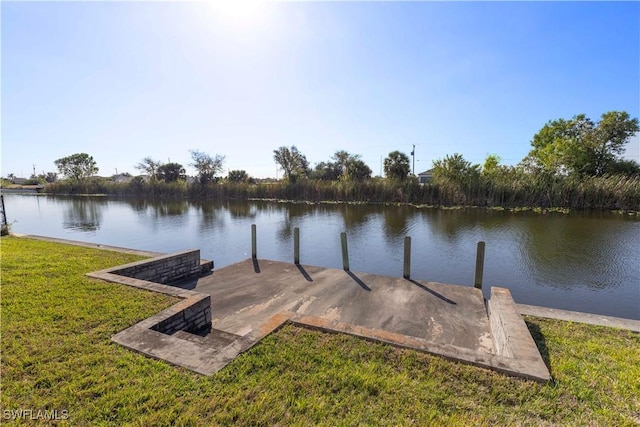 view of dock with a yard and a water view