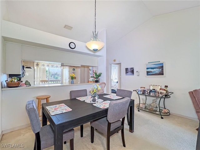 carpeted dining area featuring high vaulted ceiling