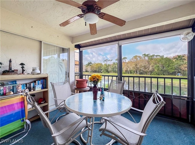 sunroom / solarium featuring a water view, plenty of natural light, and ceiling fan