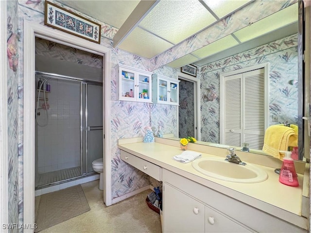 bathroom featuring vanity, a shower with door, and toilet