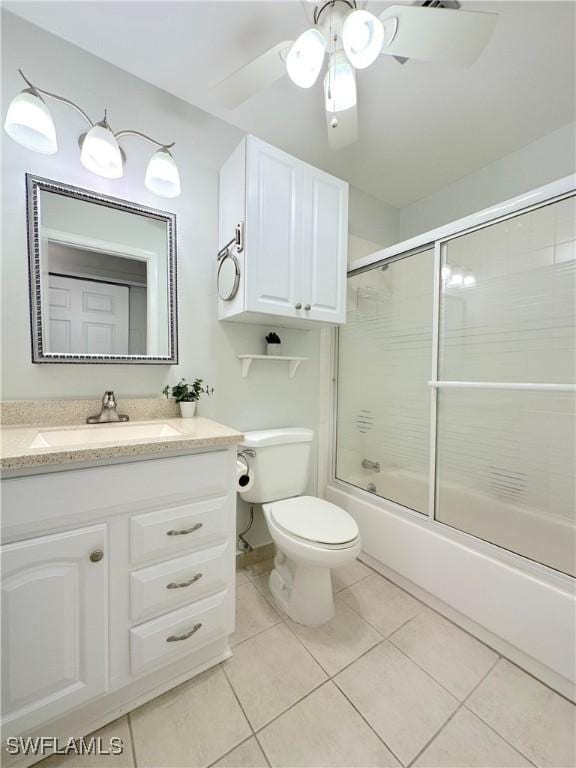 full bath with shower / bath combination with glass door, toilet, a ceiling fan, vanity, and tile patterned floors