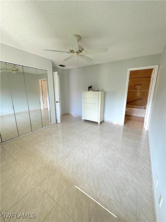 unfurnished bedroom featuring a closet, a textured ceiling, light tile patterned flooring, ceiling fan, and baseboards