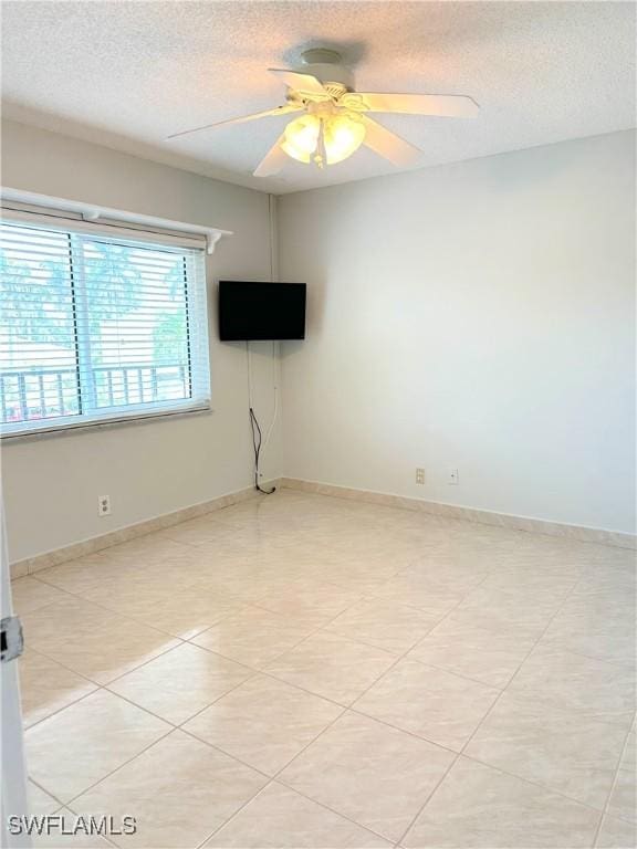 unfurnished room with baseboards, a ceiling fan, and a textured ceiling