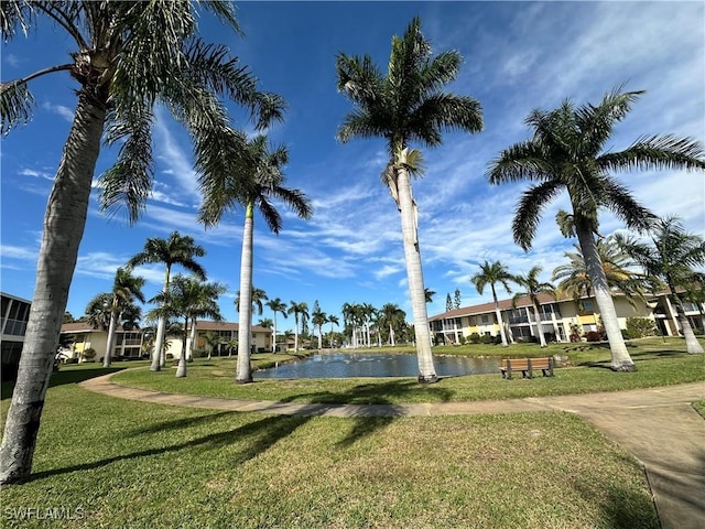 view of property's community with a water view and a lawn