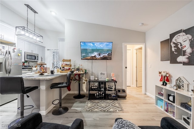 kitchen with kitchen peninsula, decorative light fixtures, appliances with stainless steel finishes, white cabinets, and a breakfast bar area