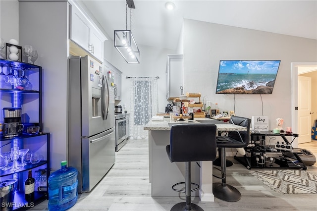 kitchen with a kitchen bar, appliances with stainless steel finishes, light stone counters, white cabinetry, and light hardwood / wood-style floors