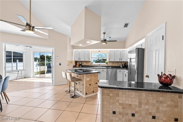 kitchen featuring white cabinets, a ceiling fan, a kitchen breakfast bar, a peninsula, and stainless steel appliances