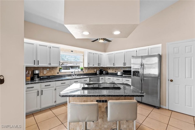 kitchen featuring a sink, stainless steel refrigerator with ice dispenser, a center island, and a kitchen breakfast bar