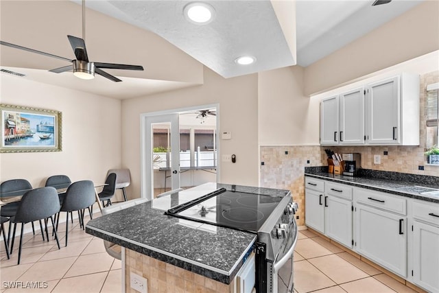 kitchen featuring light tile patterned floors, a kitchen island, visible vents, white cabinets, and stainless steel range with electric stovetop