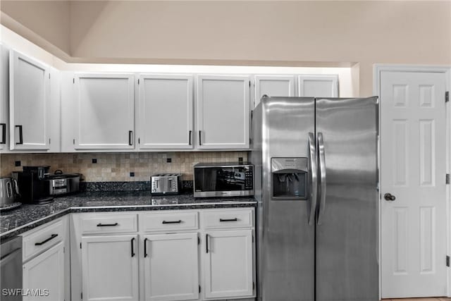 kitchen with dark stone counters, appliances with stainless steel finishes, backsplash, and white cabinets