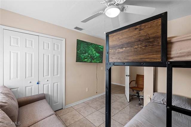 bedroom with light tile patterned floors, visible vents, baseboards, a ceiling fan, and a closet