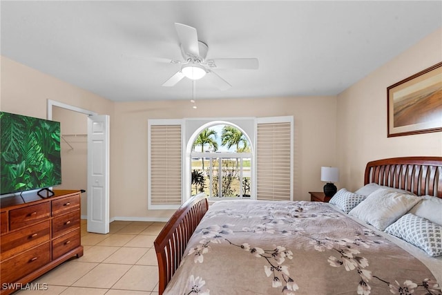 bedroom with light tile patterned flooring, ceiling fan, a spacious closet, and baseboards