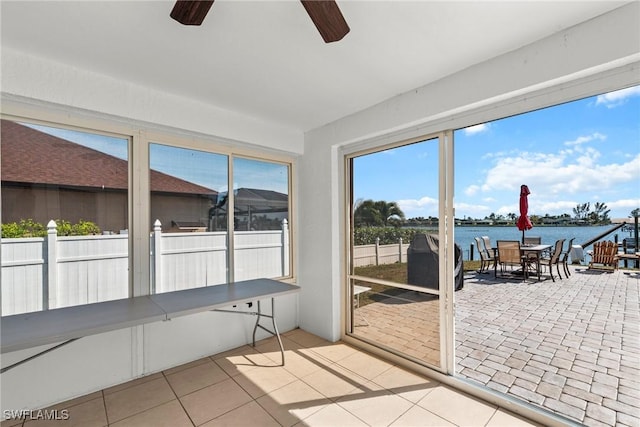 unfurnished sunroom with a water view and ceiling fan