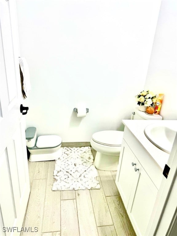 bathroom with toilet, hardwood / wood-style flooring, and vanity