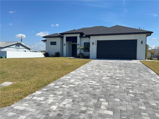 prairie-style house with decorative driveway, stucco siding, an attached garage, a front yard, and fence