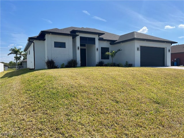 prairie-style home with a garage, stucco siding, and a front yard