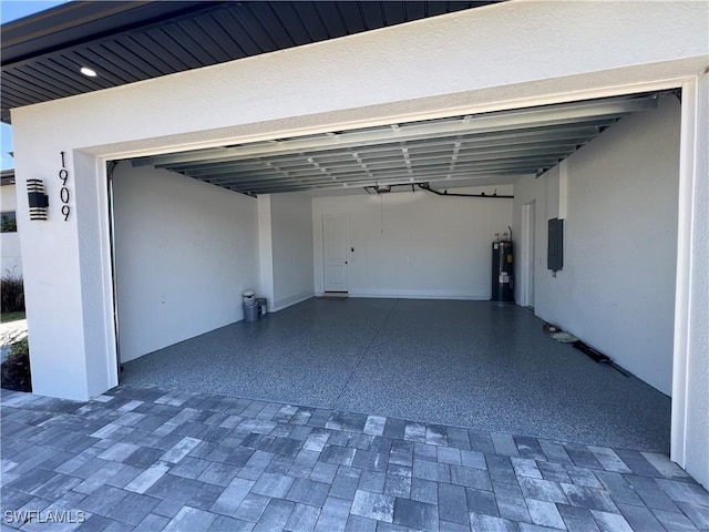 garage with a garage door opener, decorative driveway, electric water heater, and electric panel